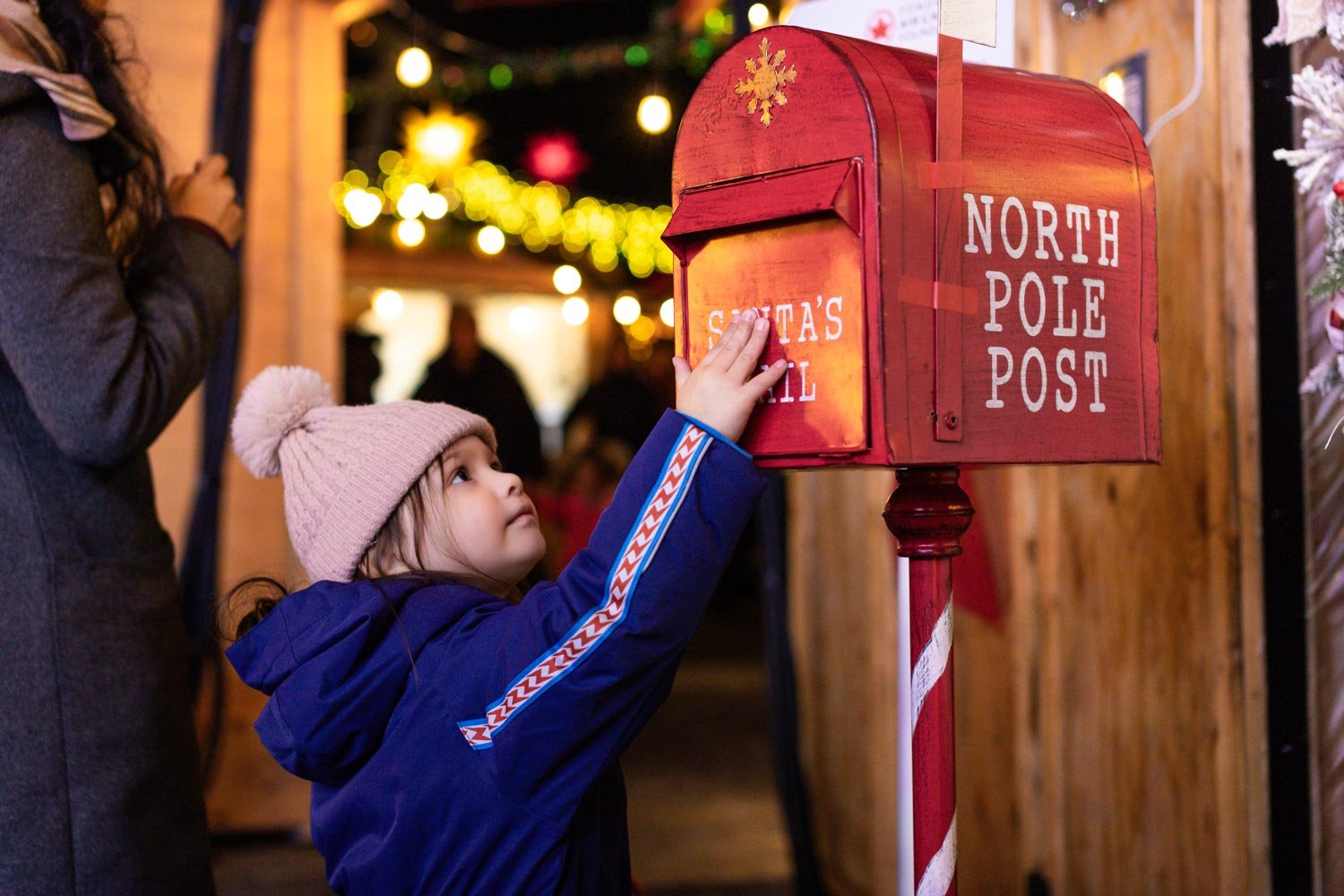 A child sending a letter at a mailbox at the Vancouver Christmas Market